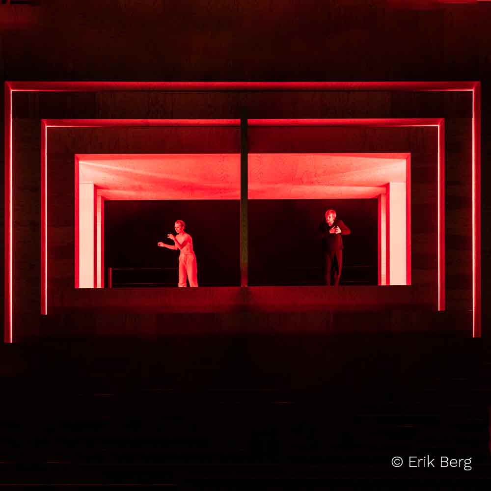 Abstraktes Bühnenbild mit rotem Lichteffekt und zwei Darstellern