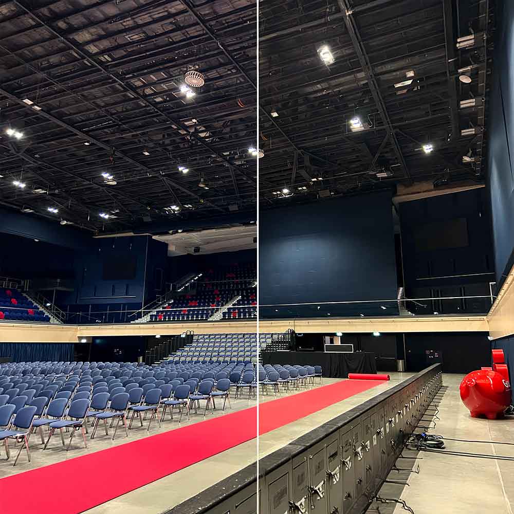 Ein leerer Veranstaltungsraum mit blauen Stühlen und rotem Teppich.