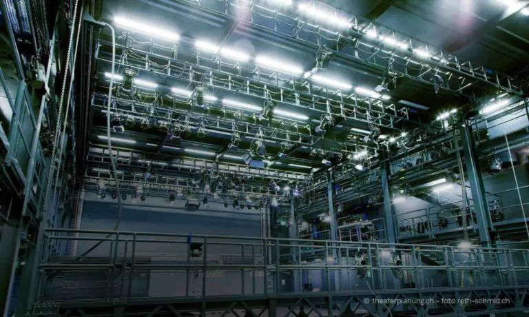 Leere Bühnenhalle mit Metallgerüsten in Grau Blau und hellen Lampen